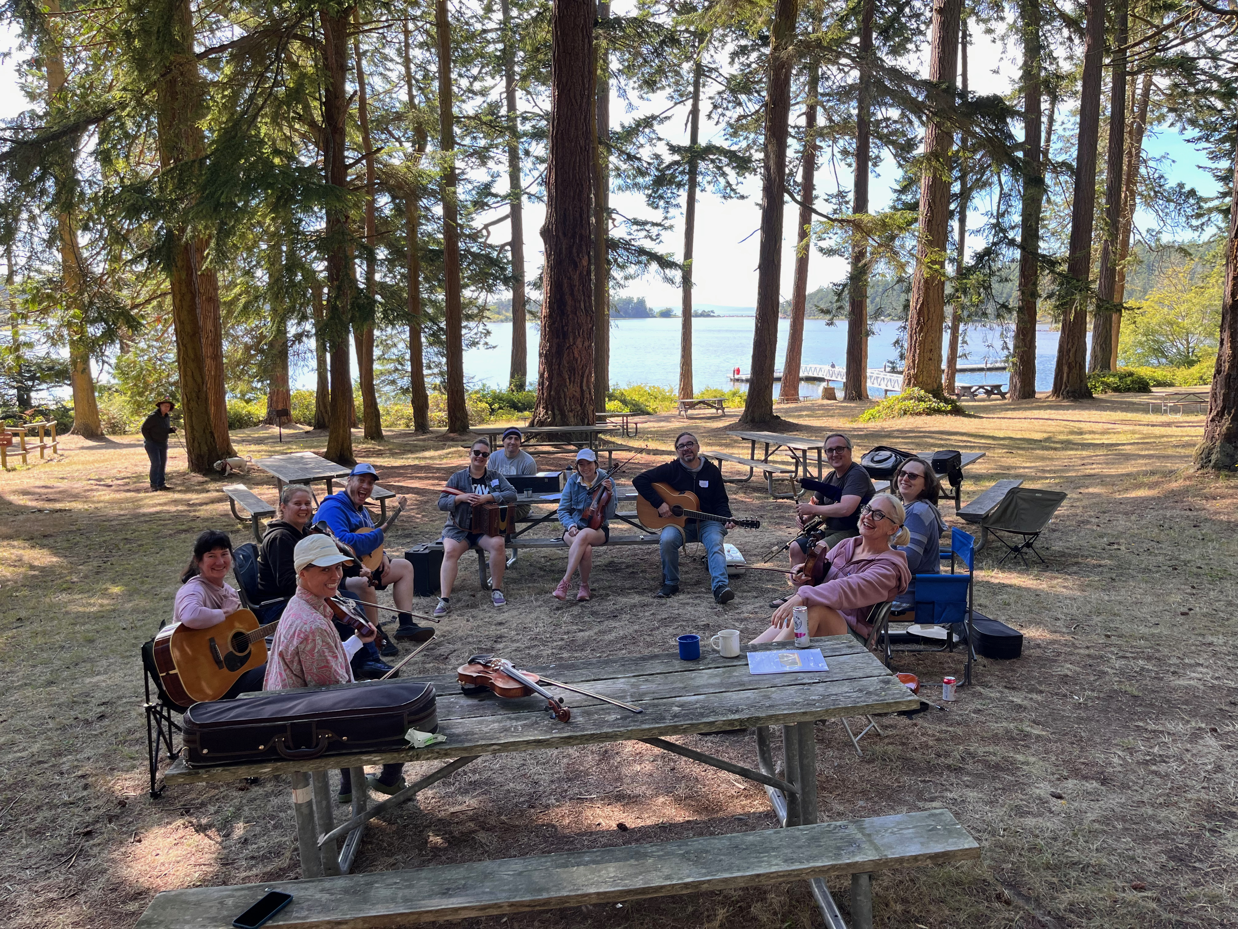 Tune sessions are a great time. people in camp chairs in the woods holding instruments