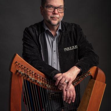 man standing behind folk harp