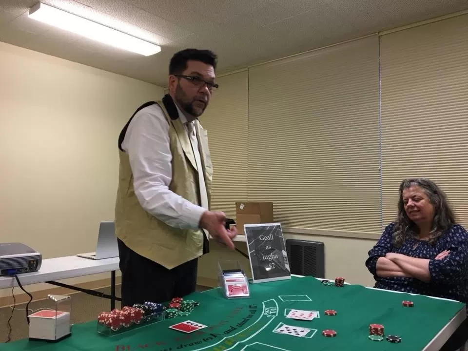 Man stands behind table with cards and casino chips.
