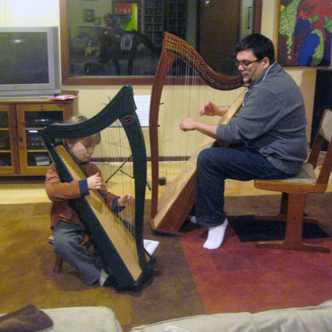 Man sits with harp facing a small boy with a harp